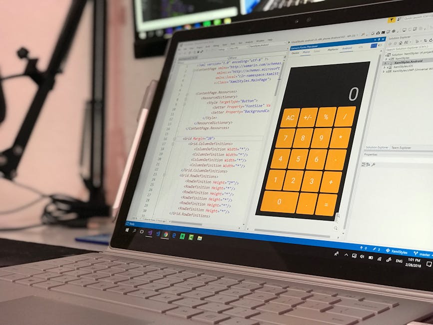 A close-up view of a laptop computer displaying a colorful calculator interface on its screen, with bright orange buttons for numbers and functions, set against a background of text editing software w
